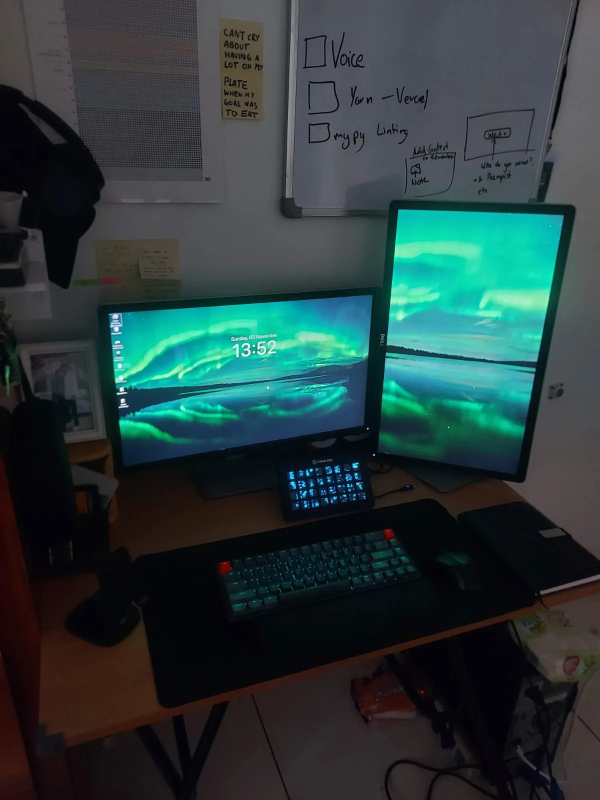 A dual-monitor setup with matching aurora wallpapers, the second screen flipped vertical, a Stream Deck and a green keyboard.