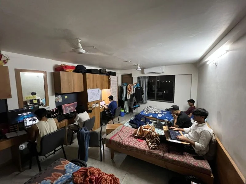 The whole GAIA team working from a PG room at night, spread across desks and beds with laptops, before a Product Hunt launch.