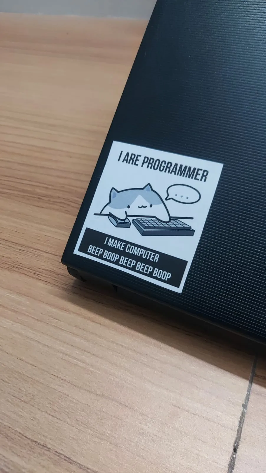 Close-up of the 'I are programmer, I make computer beep boop' sticker on the laptop corner.